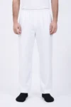 Person standing, wearing white elastic-waist pants and a white shirt, with black socks visible at the feet.