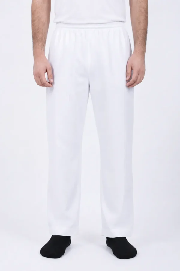 Person standing, wearing white elastic-waist pants and a white shirt, with black socks visible at the feet.