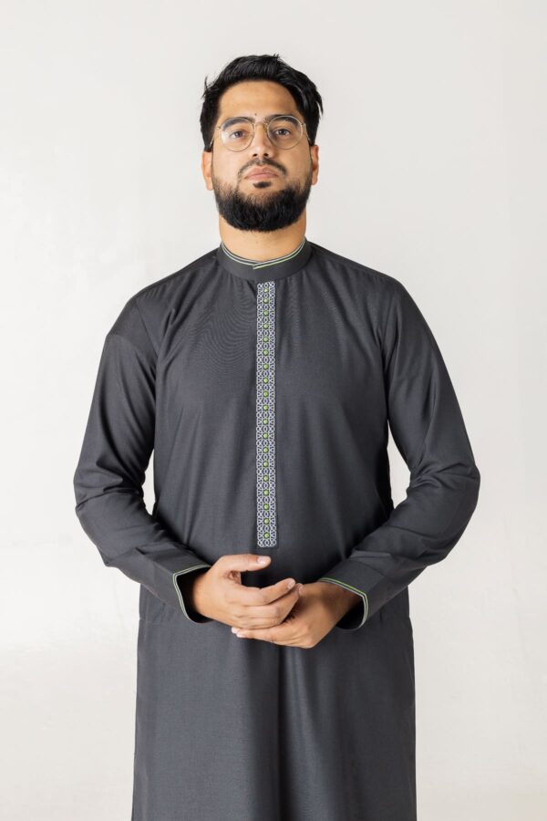 A charcoal grey custom thobe with a structured mandarin collar. The design features a slim vertical embroidered placket with a geometric pattern in white and grey, finished with subtle lime green piping on the collar and cuffs.
