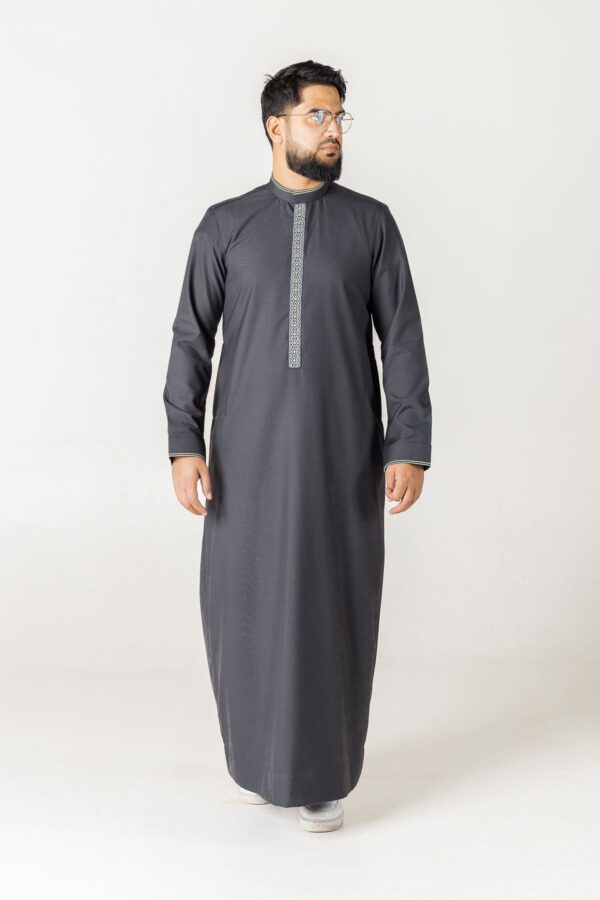 A charcoal grey custom thobe with a structured mandarin collar. The design features a slim vertical embroidered placket with a geometric pattern in white and grey, finished with subtle lime green piping on the collar and cuffs.