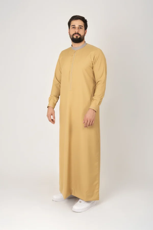 Men’s mustard yellow thobe with textured collar by alqamees. A ready-to-wear thobe featuring a modern tailored fit, tonal embroidery, and premium fabric, representing the signature craftsmanship of the alqamees collection.