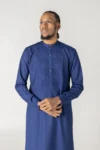 Navy blue pleated thobe for men by alqamees. A ready-to-wear thobe featuring a tuxedo-style pleated chest, mandarin collar, and premium fabric, representing the high-end tailoring of the alqamees collection.