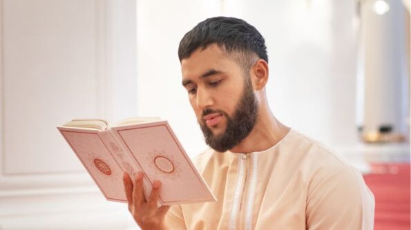 person seen in thobe reciting quran in the mosque