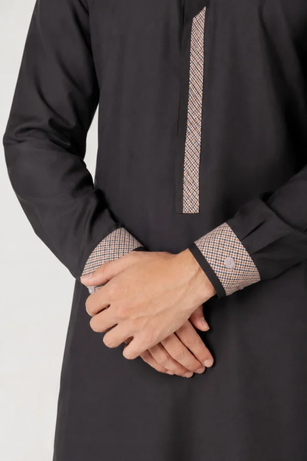 Close-up of a black kurta with patterned cuffs and front placket showing beige-check pattern.