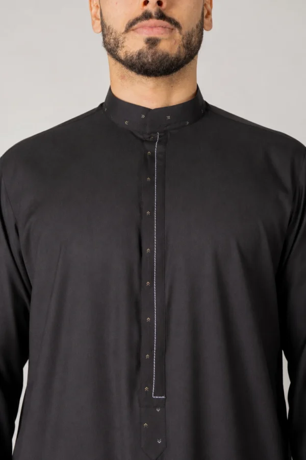 Man wearing a black kurta with a mandarin collar and a narrow stitched placket featuring small arrow-like motifs along the seam.