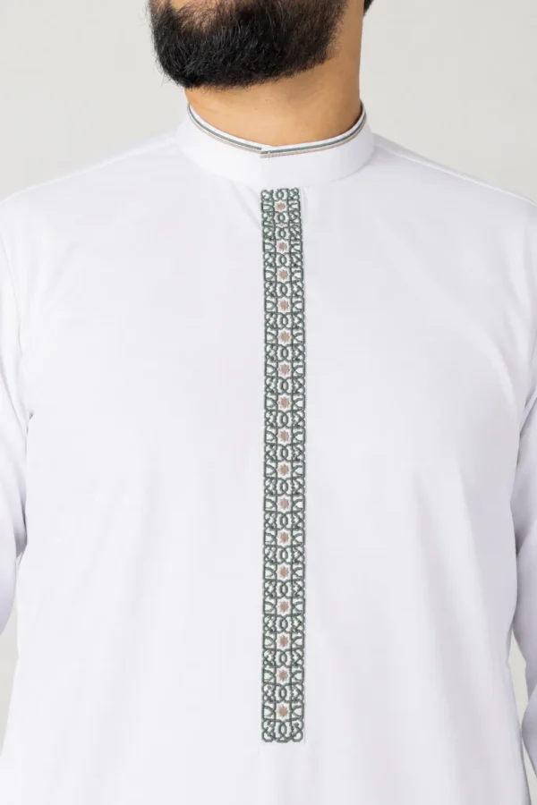 Man wearing a white traditional shirt with a dark green embroidered front placket running from the collar down the chest.