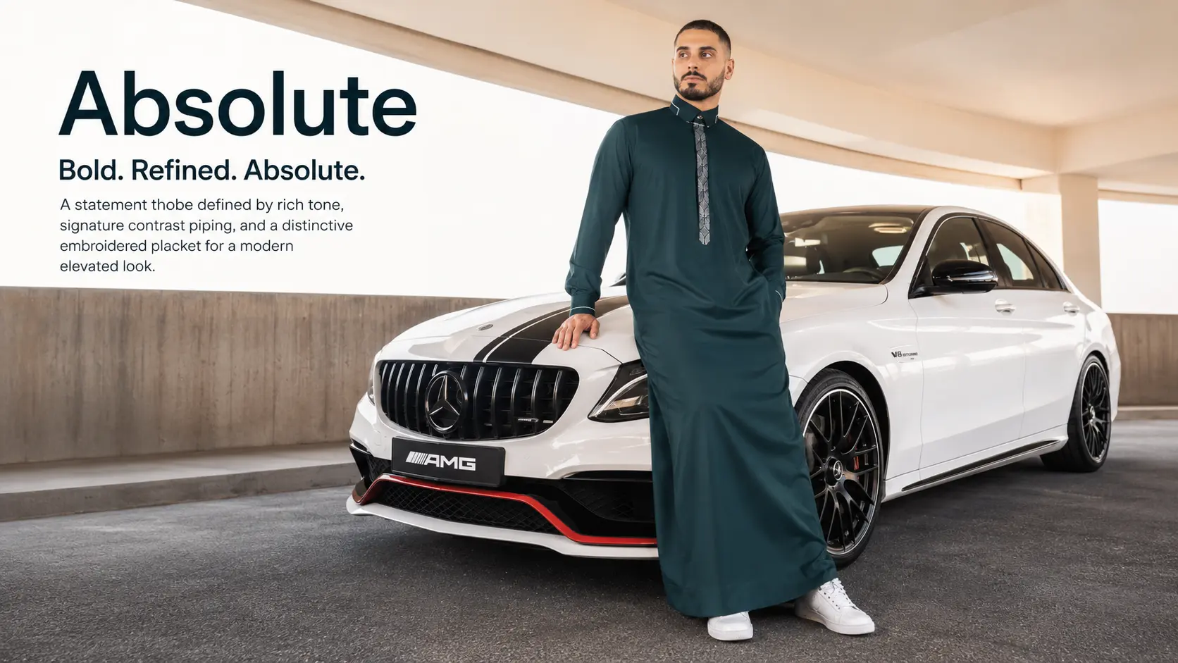 Man in a teal thobe leaning on a white Mercedes-AMG with a black stripe in a parking structure.